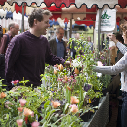Two people chattig over the plant stall at the market