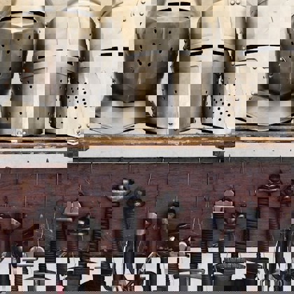 5 helmets in medieval style in a row on a shelf