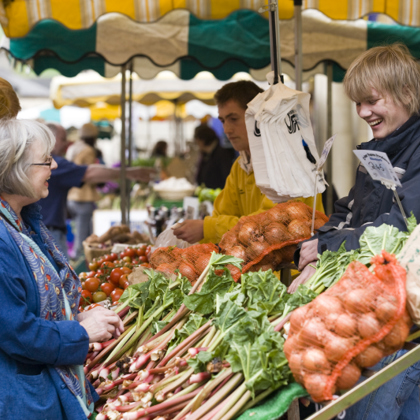two people chatting over a fruit and veg stall 